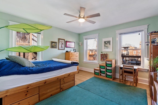 bedroom with ceiling fan, baseboards, and wood finished floors