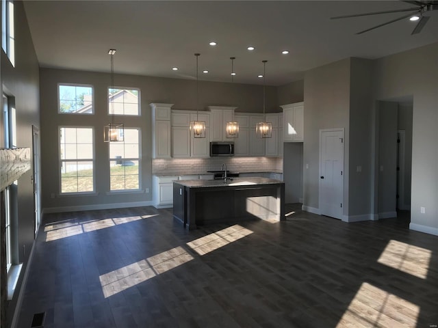 kitchen with white cabinetry, pendant lighting, dark wood-type flooring, and an island with sink