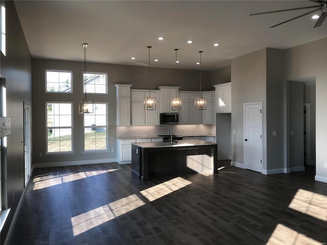 kitchen with sink, decorative light fixtures, a kitchen island with sink, and white cabinets