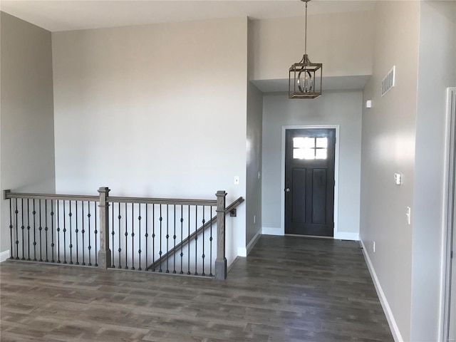 entryway with dark hardwood / wood-style floors, a notable chandelier, and a towering ceiling