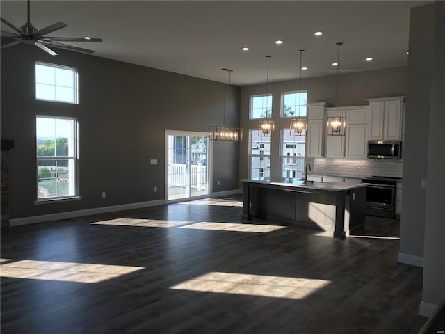 kitchen with appliances with stainless steel finishes, an island with sink, white cabinets, a kitchen bar, and decorative light fixtures