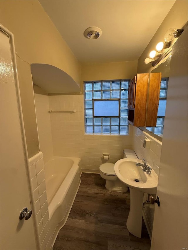 bathroom featuring toilet, wood-type flooring, tile walls, sink, and a bathtub
