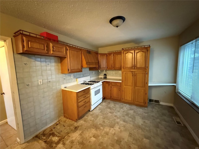 kitchen featuring a textured ceiling, white range with gas stovetop, tasteful backsplash, and custom range hood