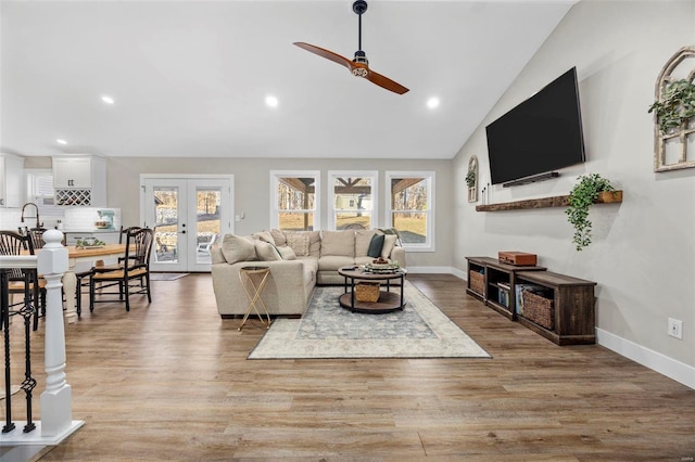 living area with light wood-style floors, a wealth of natural light, french doors, and baseboards