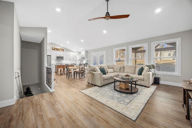 living room featuring lofted ceiling, light wood-style flooring, baseboards, and recessed lighting