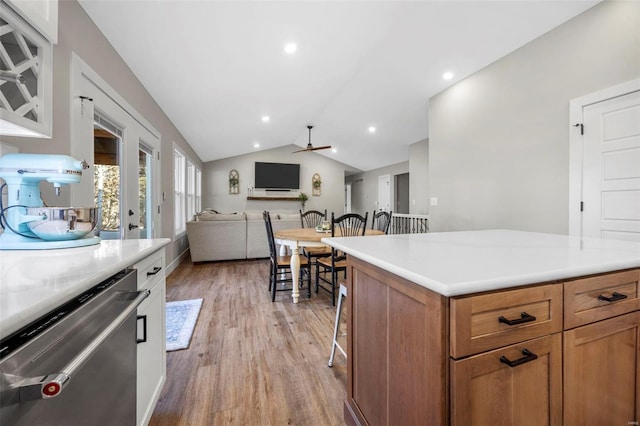 kitchen featuring lofted ceiling, a kitchen breakfast bar, open floor plan, stainless steel dishwasher, and light wood finished floors