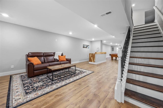 living room with light wood-type flooring, baseboards, stairs, and visible vents