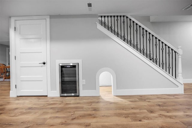 stairway with wine cooler, baseboards, and wood finished floors