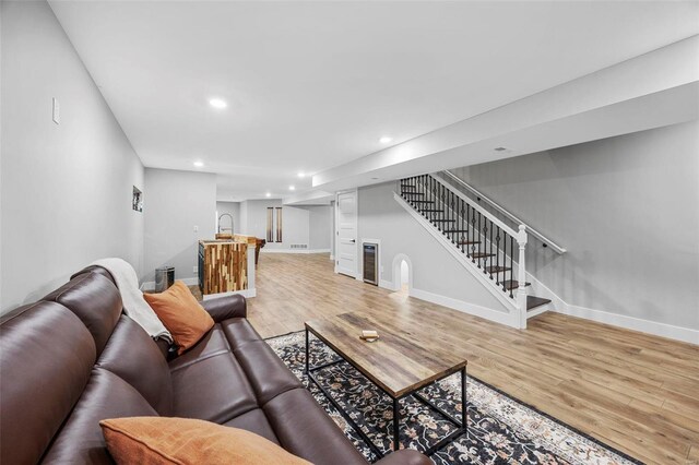 living area featuring light wood-type flooring, stairway, baseboards, and recessed lighting