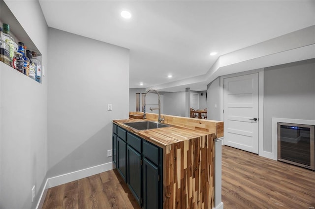 kitchen featuring dark wood finished floors, a sink, butcher block countertops, a peninsula, and baseboards