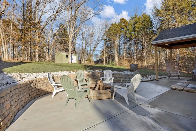 view of patio featuring an outdoor fire pit, an outdoor structure, and a storage unit