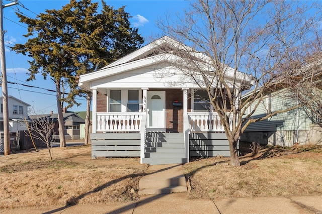 bungalow-style home with a front lawn and covered porch