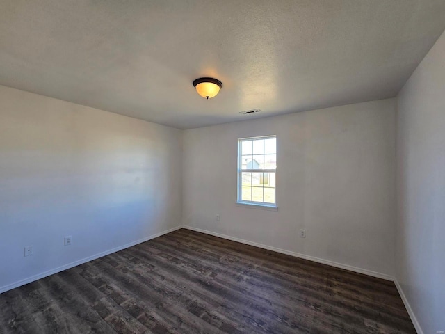 spare room featuring dark hardwood / wood-style flooring and a textured ceiling