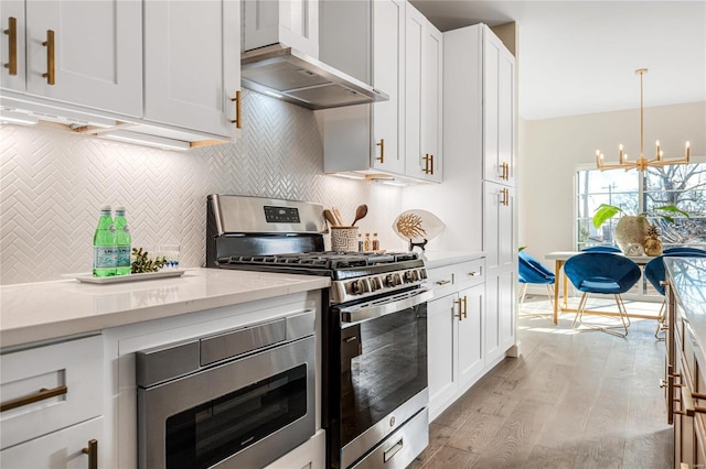 kitchen with white cabinets, stainless steel appliances, light stone countertops, wall chimney range hood, and light wood-type flooring