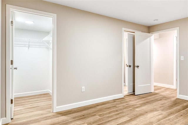 unfurnished bedroom with a spacious closet, light hardwood / wood-style floors, and a closet