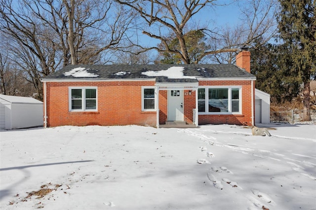 view of front facade featuring entry steps, brick siding, a chimney, and a garage