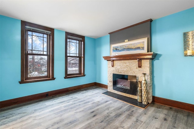 unfurnished living room with a stone fireplace and wood-type flooring