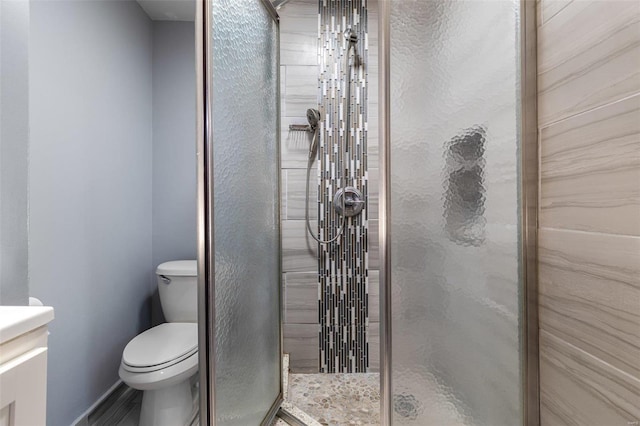 bathroom featuring vanity, toilet, and a shower with door