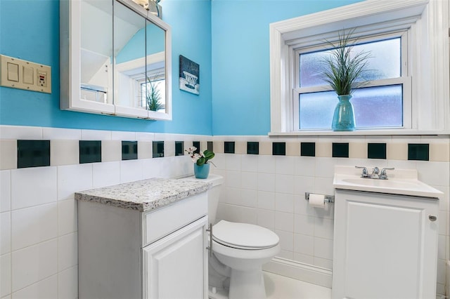 bathroom featuring vanity, toilet, and tile walls