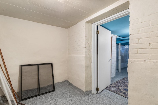 hallway with carpet flooring and brick wall