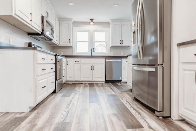 kitchen featuring white cabinetry, sink, light wood-type flooring, and appliances with stainless steel finishes