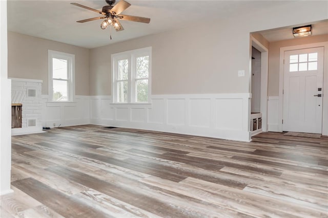 unfurnished living room with ceiling fan, hardwood / wood-style floors, and a fireplace