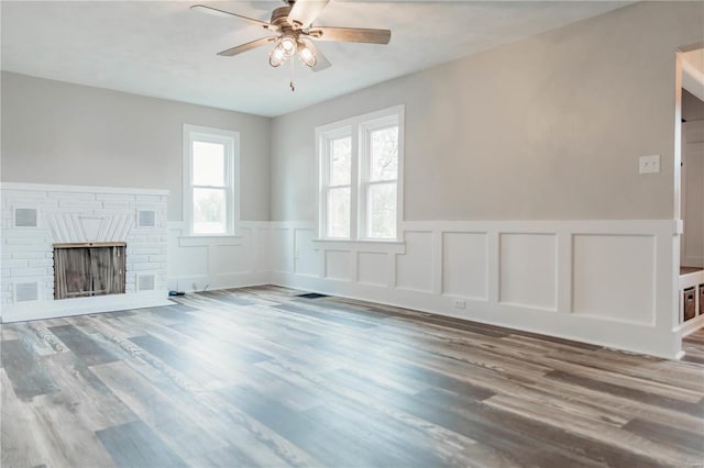 unfurnished living room featuring ceiling fan, wood-type flooring, and a fireplace