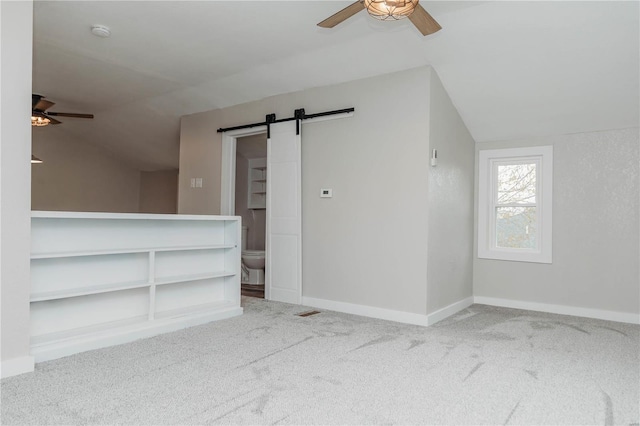 bonus room featuring light colored carpet, lofted ceiling, and a barn door