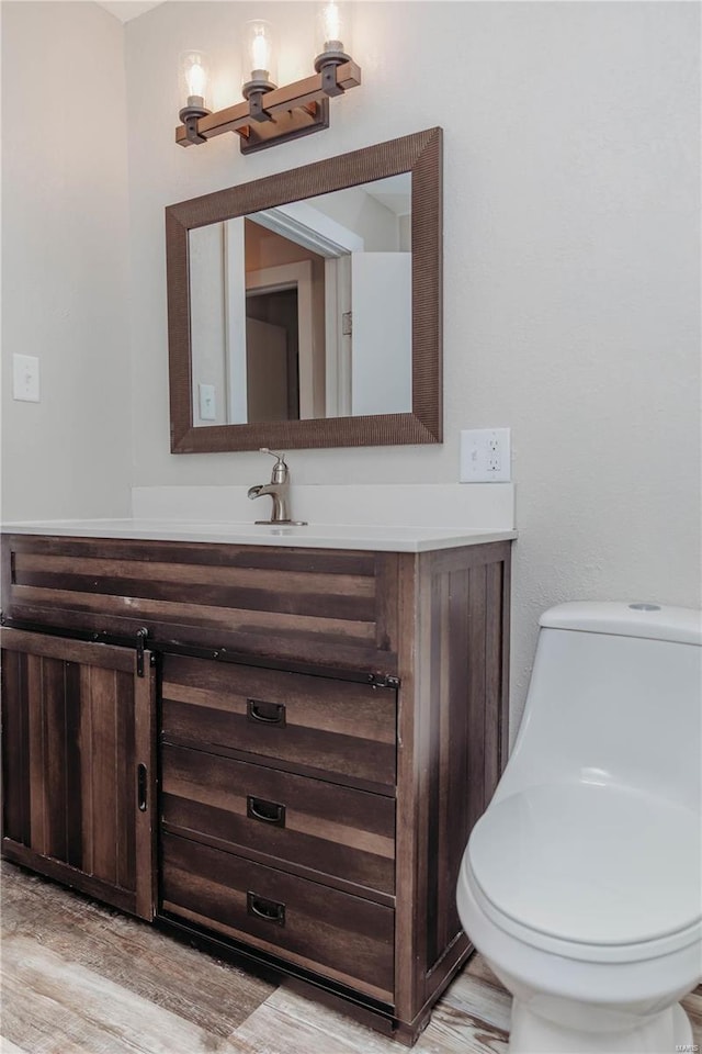 bathroom with vanity, toilet, and hardwood / wood-style floors