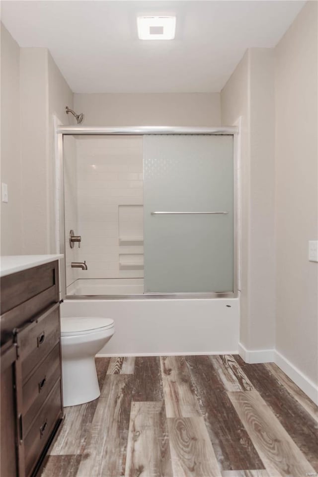 full bathroom with hardwood / wood-style flooring, vanity, toilet, and combined bath / shower with glass door