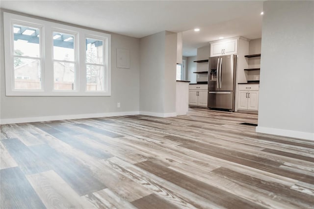 unfurnished living room with light wood-type flooring and a wealth of natural light