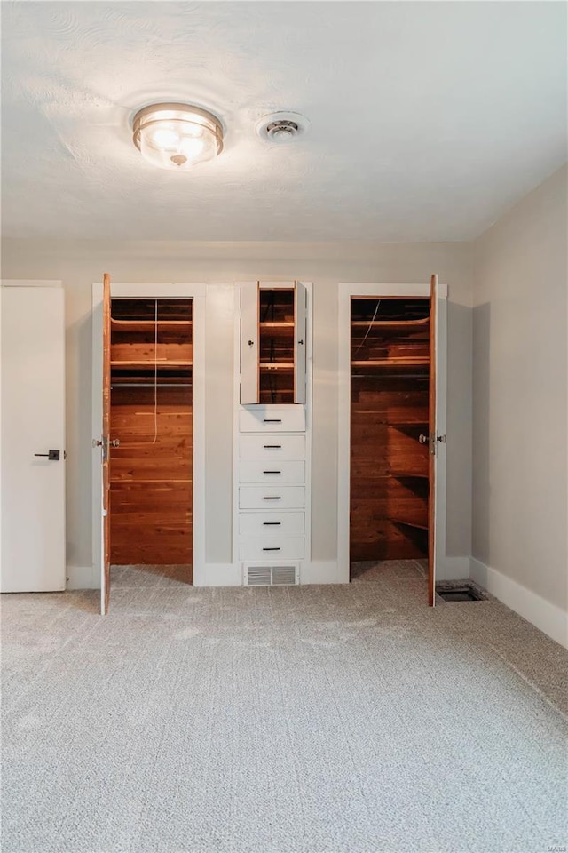 unfurnished bedroom with multiple closets and carpet flooring