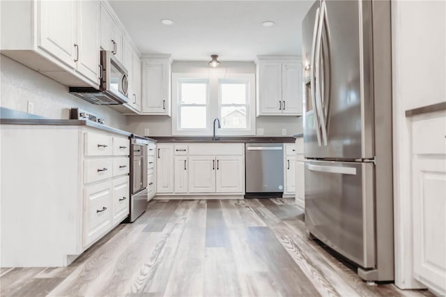 kitchen with white cabinetry, appliances with stainless steel finishes, sink, and light hardwood / wood-style floors