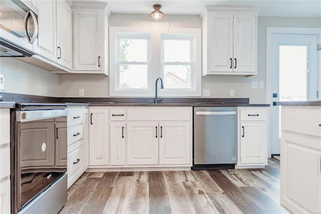 kitchen featuring sink, stainless steel appliances, white cabinets, and light wood-type flooring