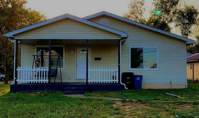 bungalow-style house featuring covered porch and a front lawn