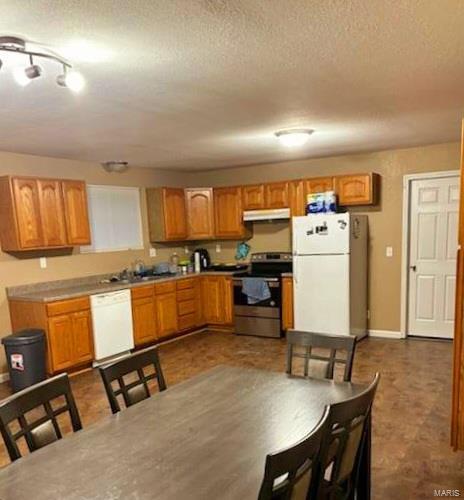 kitchen featuring sink, a textured ceiling, and white appliances