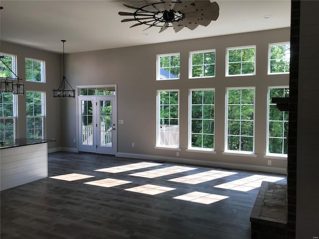 interior space featuring dark hardwood / wood-style floors, ceiling fan with notable chandelier, and a high ceiling