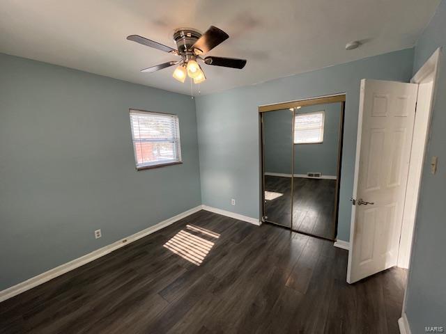 unfurnished bedroom featuring dark hardwood / wood-style floors, ceiling fan, and a closet