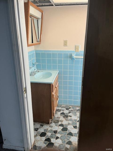 bathroom featuring vanity and tile walls