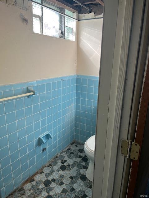 bathroom featuring tile walls and toilet