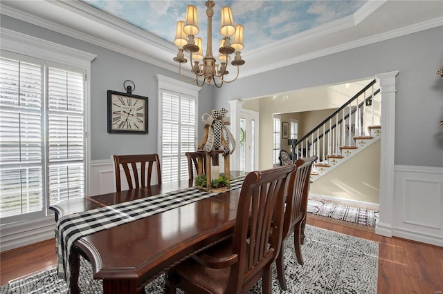 dining area featuring decorative columns, a raised ceiling, dark hardwood / wood-style floors, and an inviting chandelier