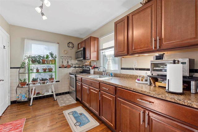 kitchen featuring tile walls, sink, stainless steel appliances, and light hardwood / wood-style floors