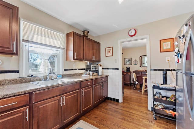 kitchen featuring tile walls, sink, dark wood-type flooring, and stainless steel refrigerator