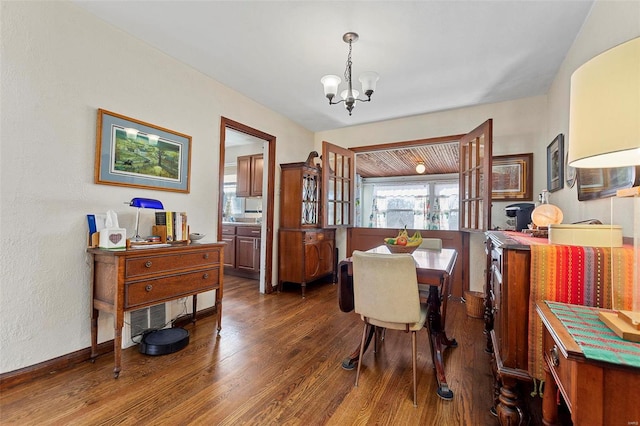 dining room with dark wood-type flooring and an inviting chandelier