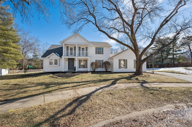 greek revival house with a balcony, a front yard, and french doors