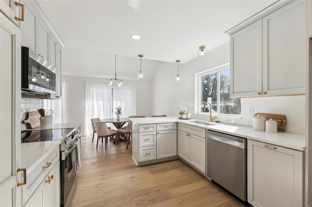 kitchen with sink, backsplash, hanging light fixtures, kitchen peninsula, and stainless steel appliances