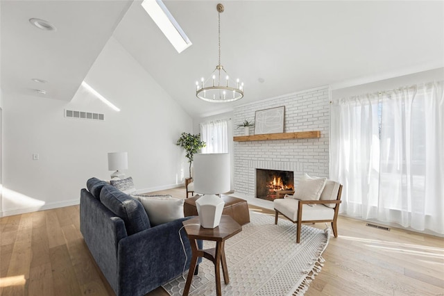 living room featuring wood-type flooring, a healthy amount of sunlight, an inviting chandelier, and a fireplace