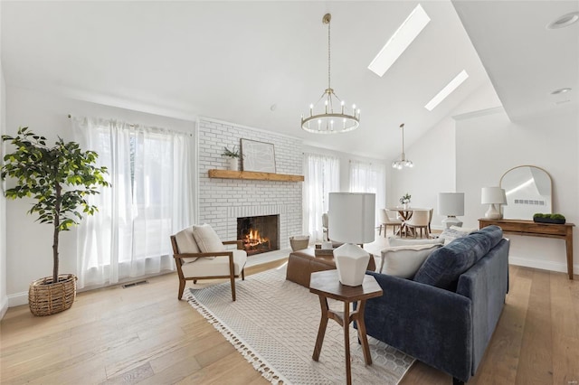 living room featuring a skylight, a wealth of natural light, a notable chandelier, and light hardwood / wood-style flooring