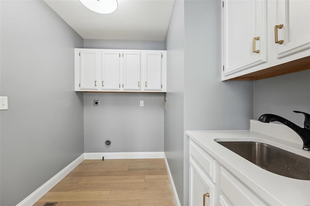 laundry room featuring cabinets, sink, hookup for an electric dryer, and light wood-type flooring