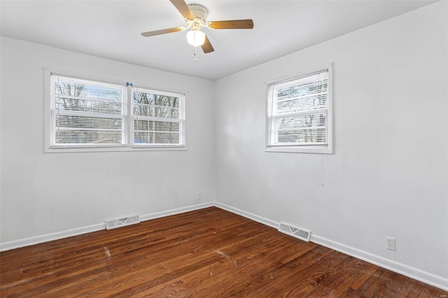 empty room featuring plenty of natural light, dark wood-type flooring, and ceiling fan